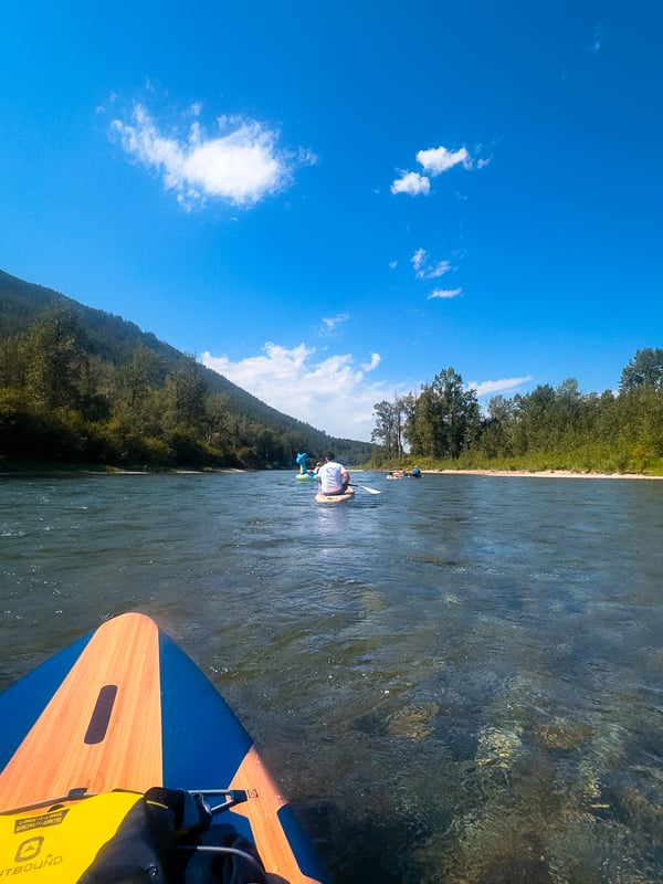 People floating down a clear river on a sunny, blue day.