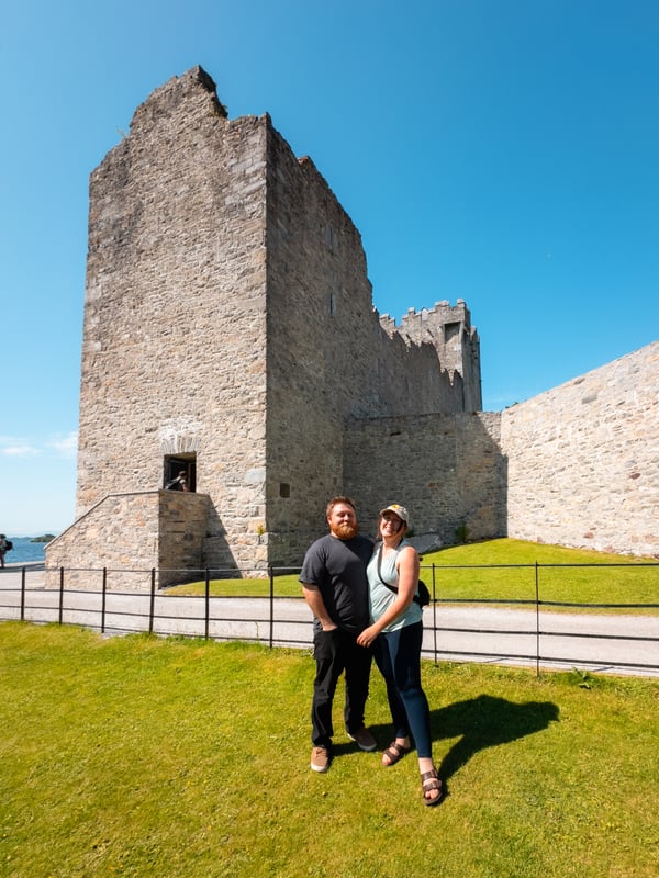 Man and woman stand in front of a historic castle, Ross Castle