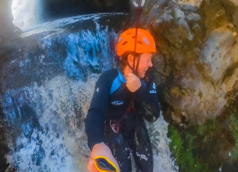 A woman ziplines over a large waterfall