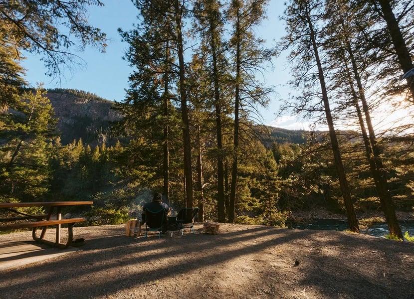 Man sitting on camp chairs near the firepit at a campsite on the Similkameen River