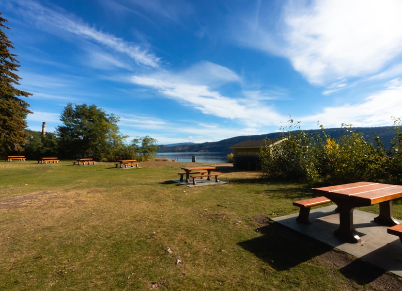 Picnic benches at the day-use area of Bear Creek Provincial park on the shores of Okanagan Lake