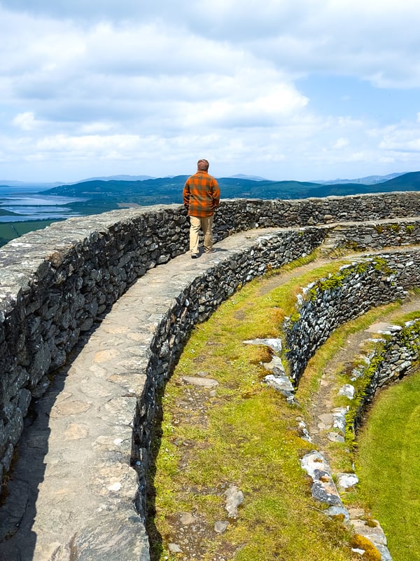 A man walks on a circular stone walkway in a historic fort.