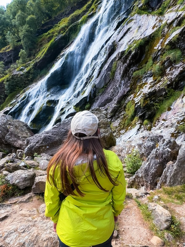 A woman stands at the bottom of a large waterfall that's a bit of a hidden gem.