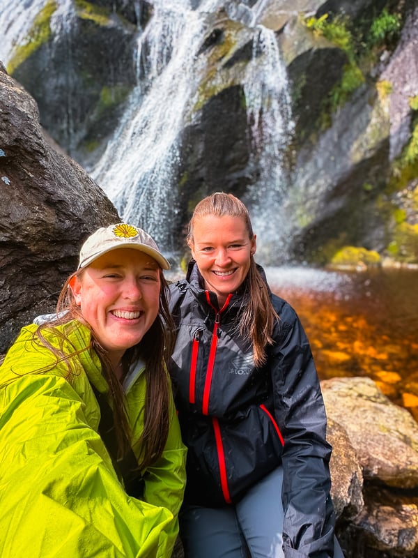 Selfie of two women at the base of a waterfall.