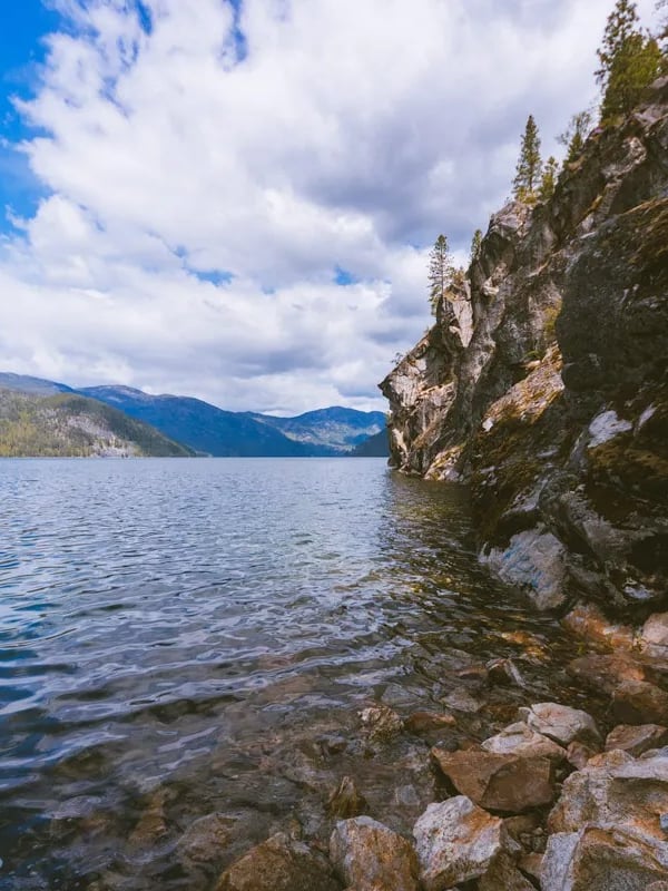 Steep, rocky cliff extends into a lake