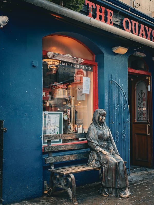 A statue of a woman sitting on a bench in Galway, Ireland