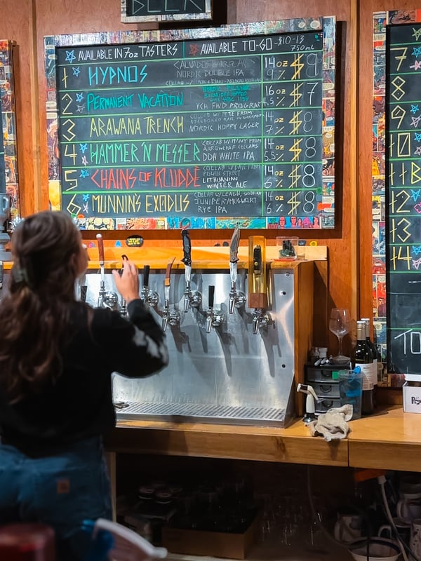Bartender pours a beer with a menu behind her