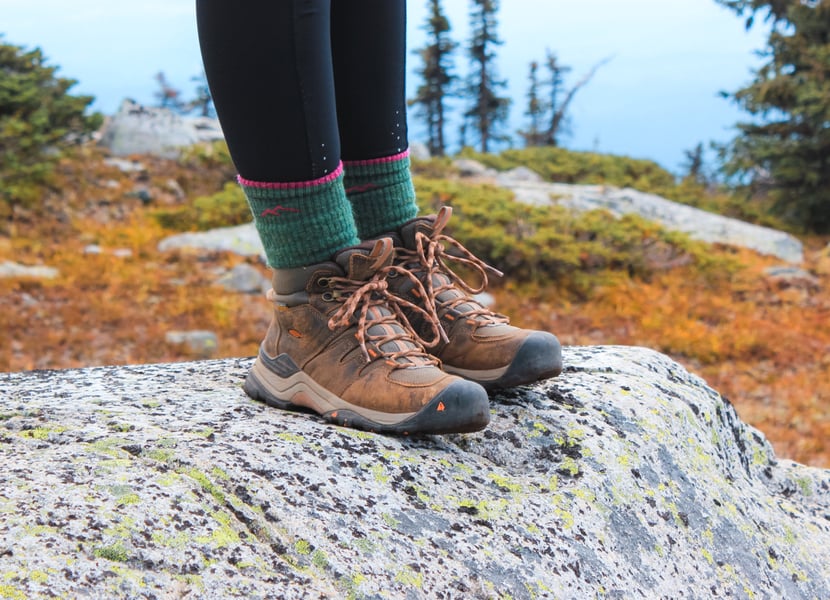 Closeup of hiking boots. Women standing on a rock.