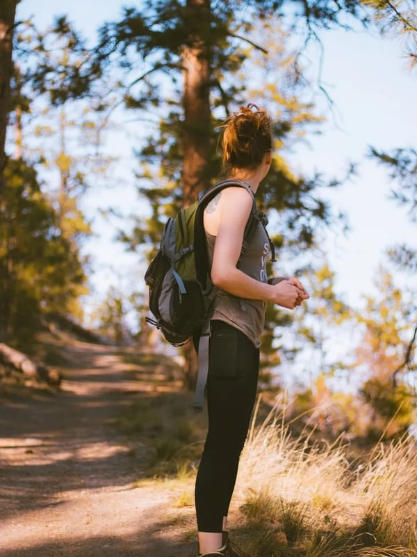 A woman with a backpack looks back at the trail.