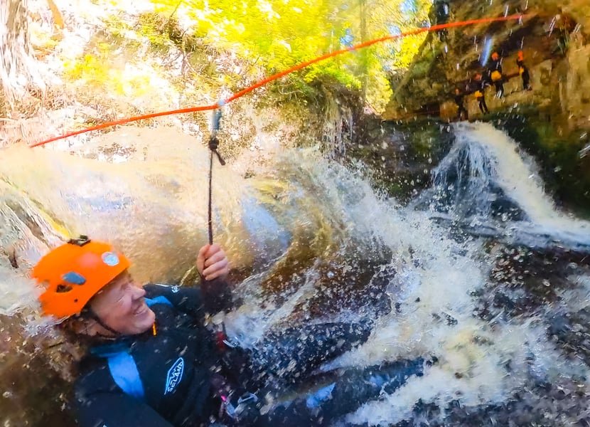 A woman lands in water after ziplining in a canyon
