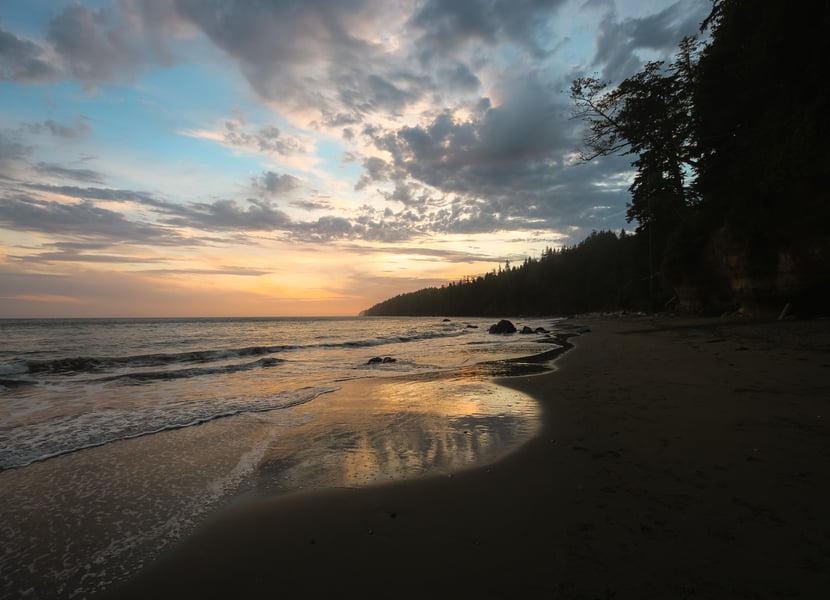 Sunset over Mystic Beach, with the sky glowing in warm colours and the ocean in the foreground.