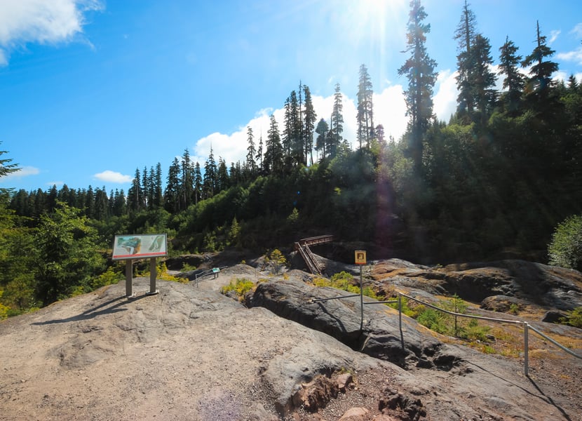 End of the paved section of the Lava Canyon Trail with trail signs and views into the canyon near Mount St. Helens