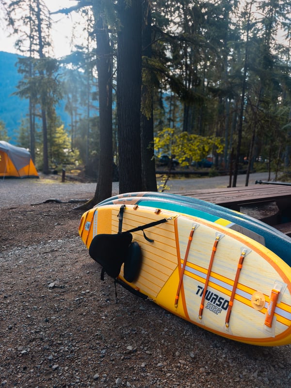 Three paddleboards leaning against each other in a campground
