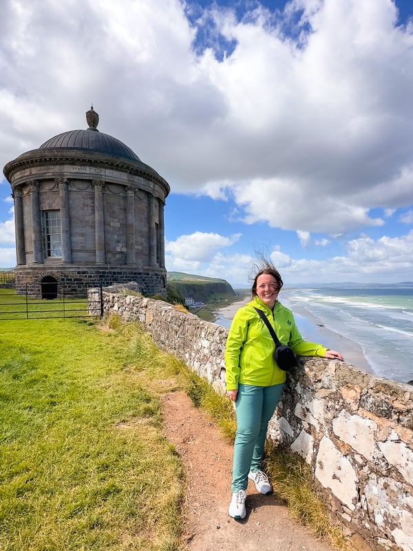 Woman standing in front of the Mussenden Temple in Northern Ireland with views of the ocean