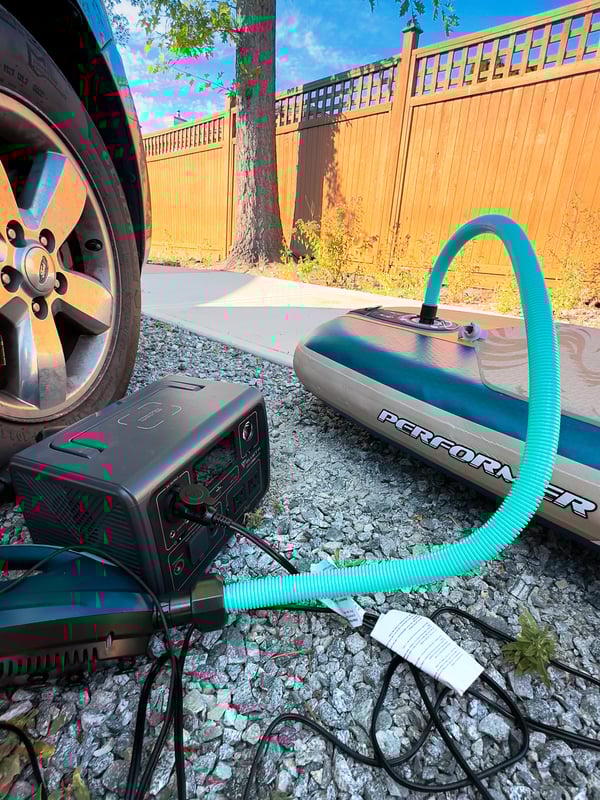 Blowing up a paddleboard at the edge of the road.