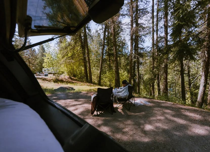 View from the back of a converted SUV at a campsite with a firepit