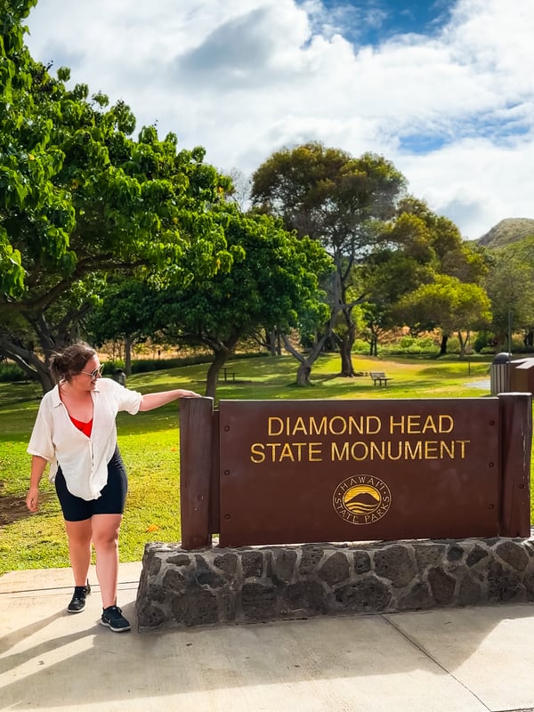 Woman stands at the Diamond Head State Monument sign.