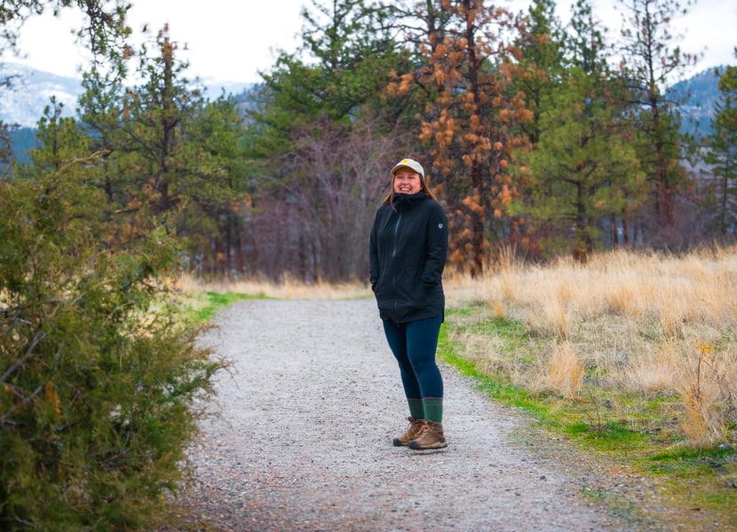 Woman laughing on a hiking trail on a rainy day.