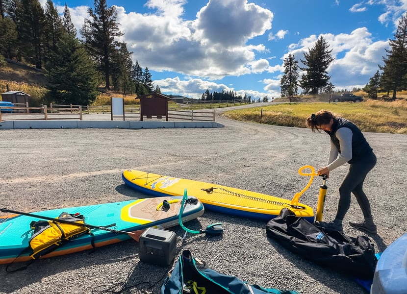 Bluetti AC70 blowing up a paddleboard while a friend pumps her paddleboard by hand.