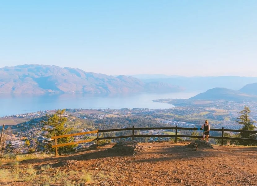 Woman standing at the summit of Mt Boucherie hike in West Kelowna, overlooking Okanagan Lake.