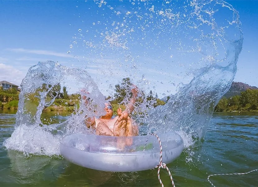 Man splashes water while floating on the Enderby River.