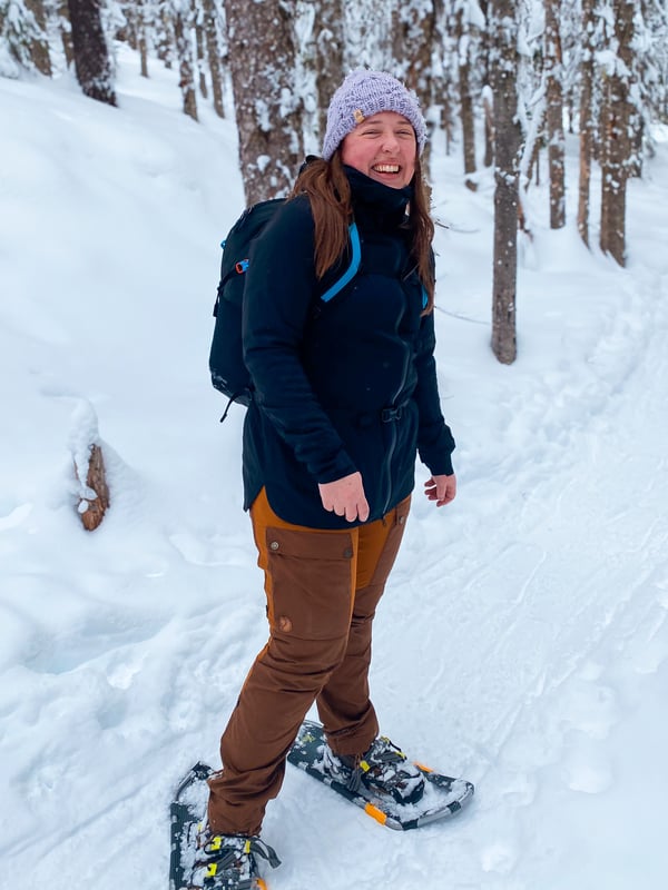 A woman facing the camera on a snowy day while snowshoeing.