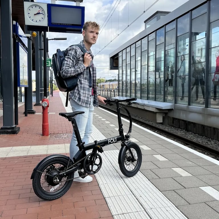 Forens met opgevouwen elektrische fiets in de trein