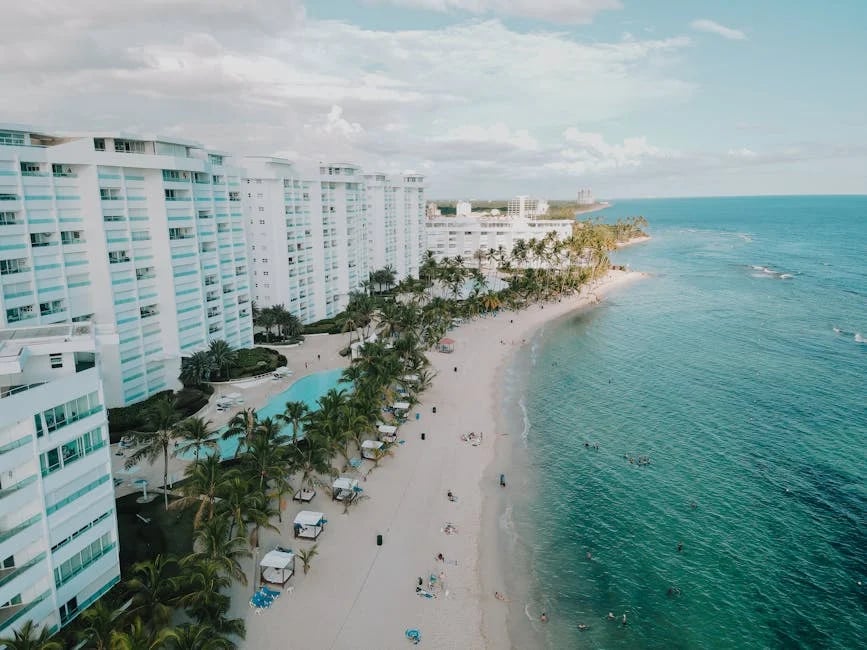 "Spacious living room with floor-to-ceiling windows overlooking the beach, listed in 'Top 10 Best Beach Condos to Buy in 2025'."