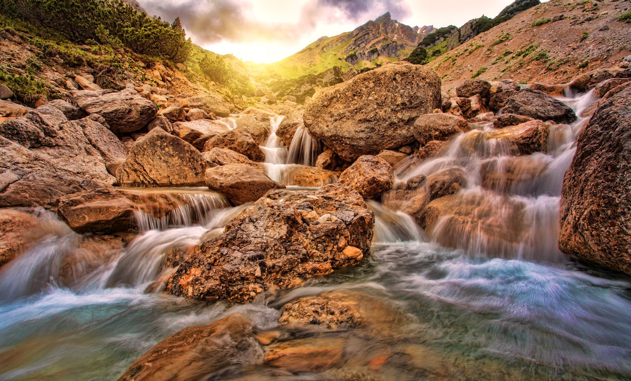 hiker filling water bottle mountain stream