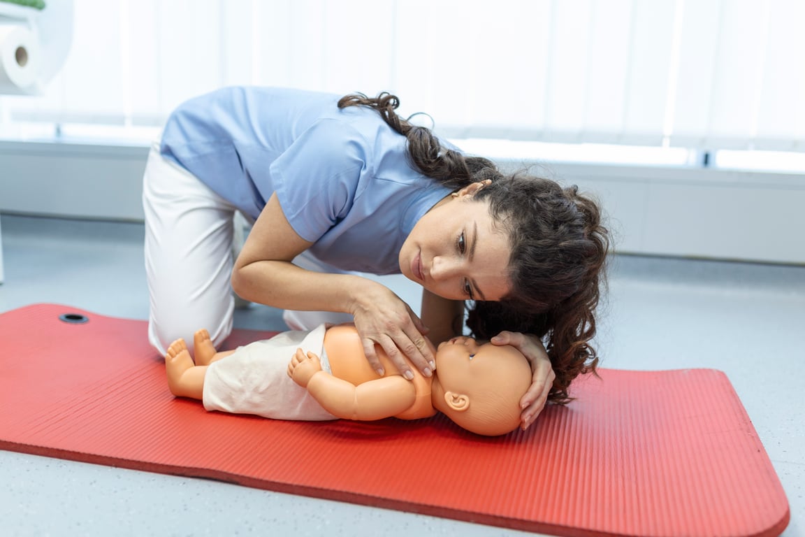 A person placing their ear next to an infant CPR dummy's mouth