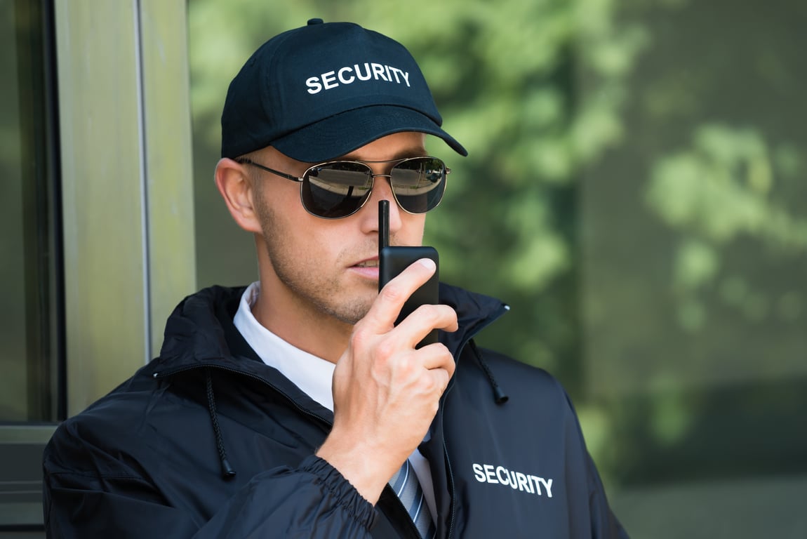 A security guard speaking into a radio