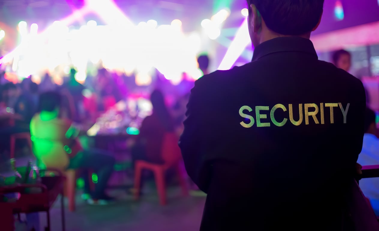 A security guard looks surveying a crowd of people at a venue