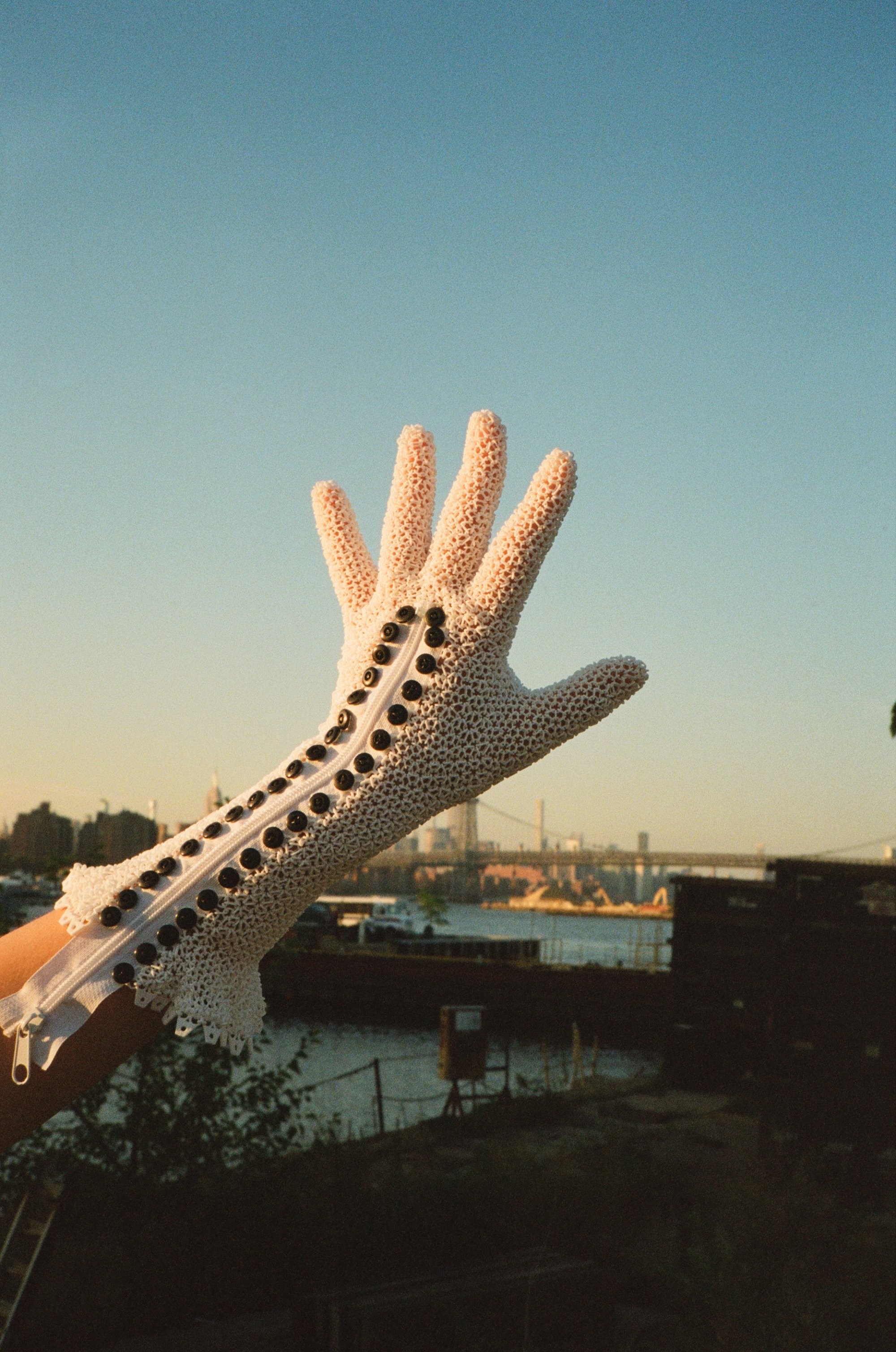 A studded Starsuit glove with fingers spread against the sky