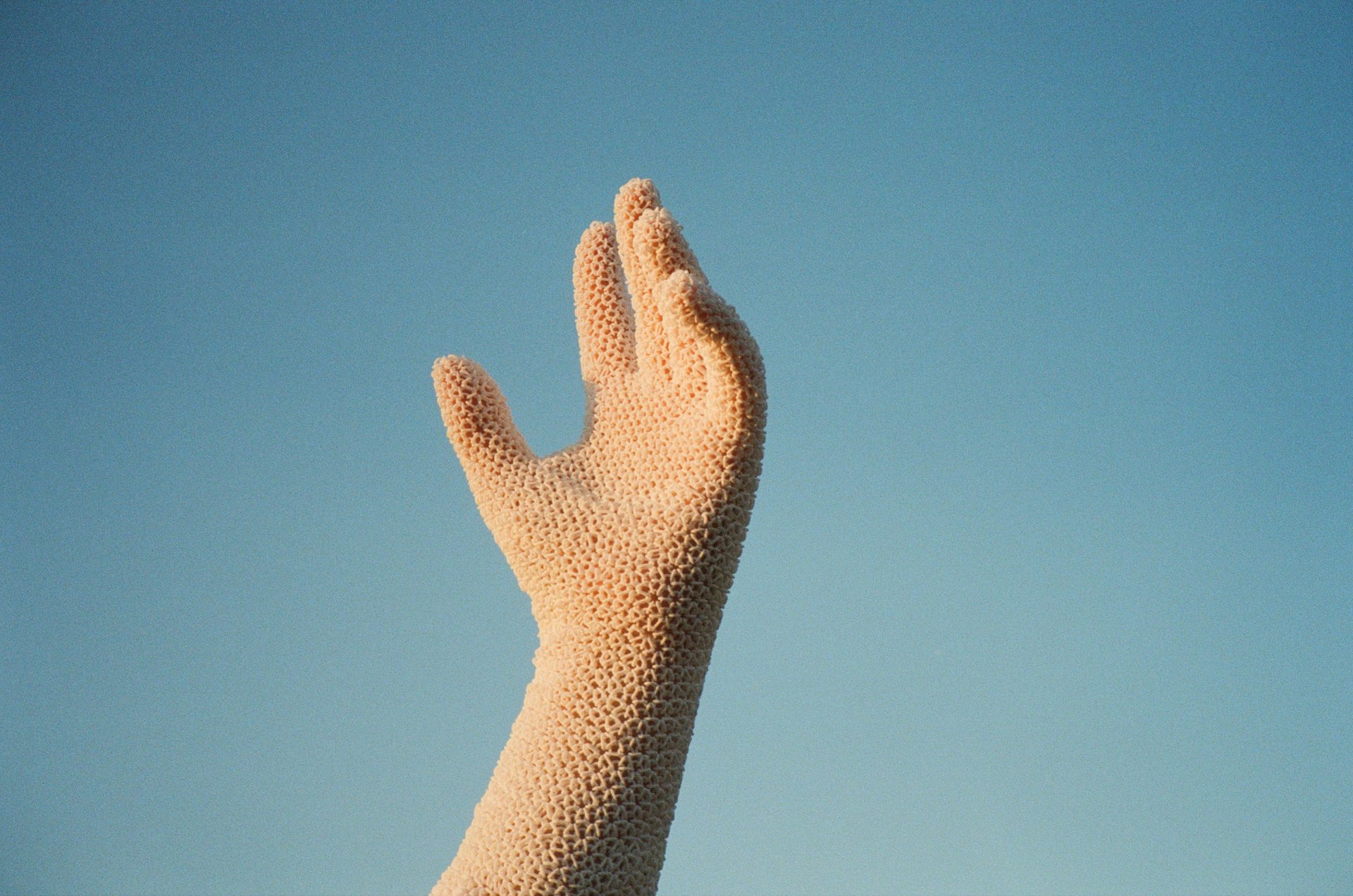 A gloved hand outstretched against a clear blue sky