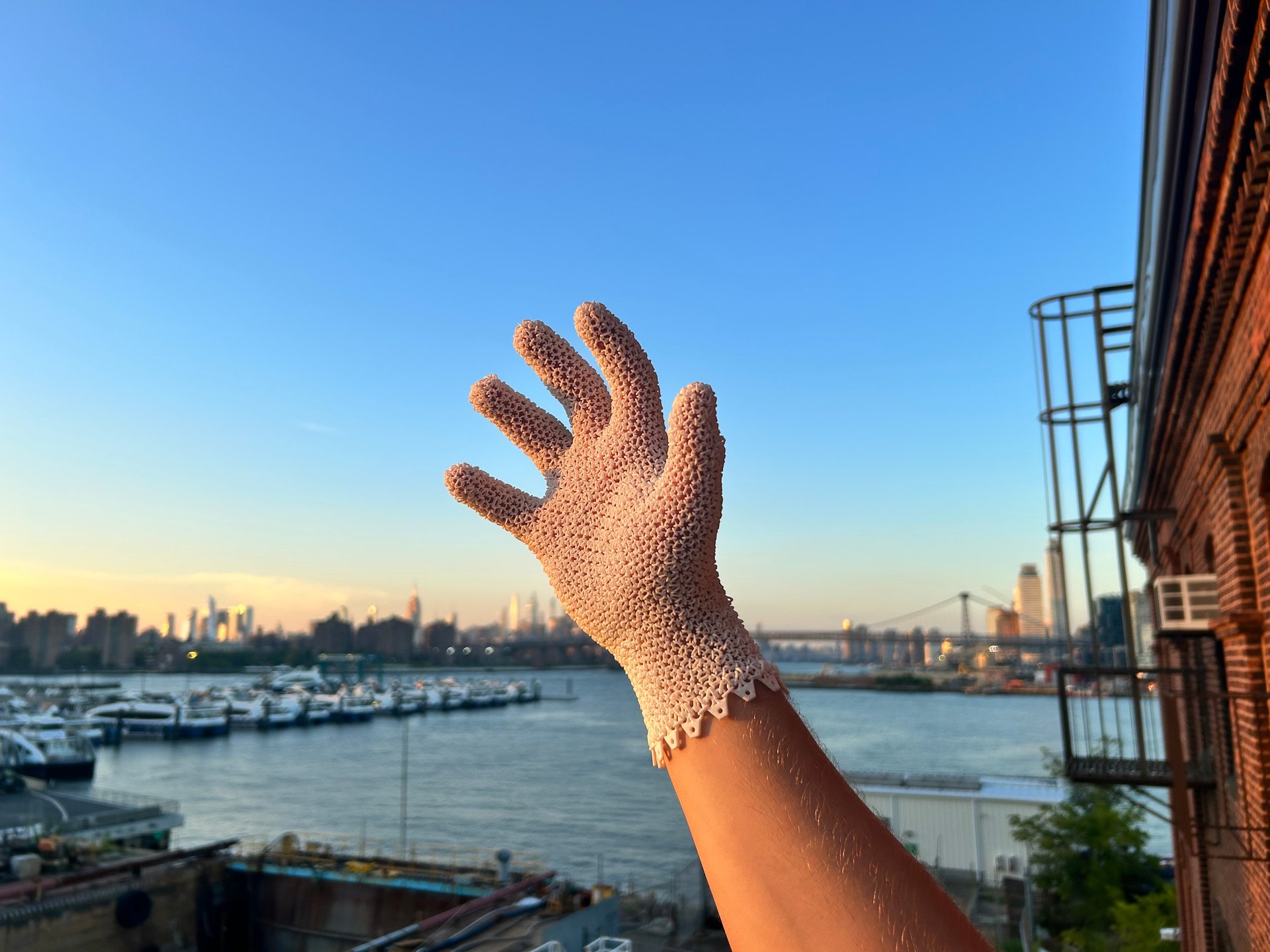 A printed Starsuit glove held up against the Manhattan skyline at sunset