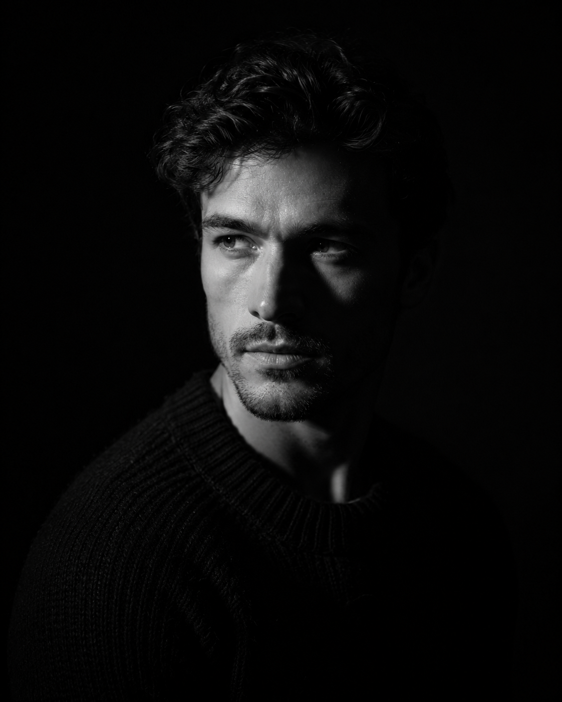 Close-up male portrait with Rembrandt lighting, single key light high at 45 degrees to the left, small triangle of light on right cheekbone, deep shadow on right side