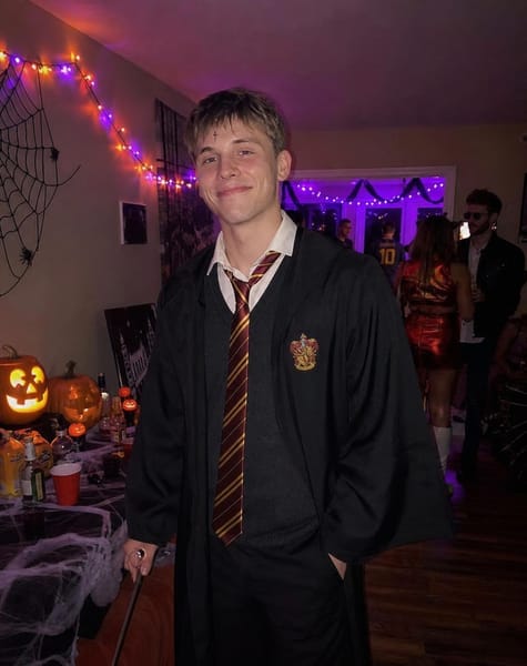 Create an ultra-realistic candid iPhone photograph of ME at a Halloween house party, dressed in a recognizable Harry Potter-inspired costume. The final image must look like a real young man attending a friend’s Halloween party, not a fantasy film still, professional cosplay photoshoot, or AI-generated character portrait.
CRITICAL FACE IDENTITY PRESERVATION: The uploaded face reference is the identity source and must take priority over every styling instruction. Preserve my exact facial identity, original face shape, eyes, eyebrows, nose, lips, jawline, skin tone, and natural facial proportions. It must unmistakably look like the same person in my reference photo. Do not replace my face with a generic handsome male face, do not beautify or reshape it, and do not alter my age or ethnicity. Change only the clothing, setting, and Halloween styling. Keep my natural facial features visible and unobstructed.
HARRY POTTER HALLOWEEN COSTUME: A recognizable, wearable Harry Potter-inspired outfit: a black Hogwarts-style robe worn open over a white collared shirt, a loosely knotted red-and-gold striped tie, a dark grey knitted V-neck sweater, and a small lightning-shaped scar drawn naturally on the forehead. Carry a simple wooden wand casually in one hand. The costume should look like something someone put together for an actual Halloween party, not a luxurious fantasy costume. No elaborate armor, no royal robes, no magical transformation.
HAIRSTYLE: Natural, slightly messy dark hair with a casual fringe. Keep the hairstyle believable for a party and do not let it change the person’s facial identity.
HALLOWEEN PARTY ENVIRONMENT: A real friend’s apartment or house decorated for Halloween. Include a few carved pumpkins, orange and purple string lights, black streamers, small spiderweb decorations, drinks on a table, and other party guests dressed in different Halloween costumes in the background. The room should feel lived-in, fun, and slightly messy in a realistic way. Make it obvious that a Halloween party is happening, rather than an empty castle or fantasy hallway.
POSE & EXPRESSION: A relaxed, spontaneous party moment. I am standing casually near the living-room decorations, holding the wand loosely and looking toward the camera as a friend takes a quick picture. Natural shoulders, slightly imperfect posture, a subtle confident expression, and relaxed body language. Do not pose me like a fashion model or movie hero.
CAMERA & FRAMING: Vertical 4:5 iPhone photograph, taken by a friend from approximately 2–3 metres away. Medium-long framing from around mid-thigh to above the head, with the costume and party background clearly visible. My face should remain recognizable without filling the entire frame. Keep the camera perspective natural, with realistic body proportions and a little space around me.
LIGHTING: Authentic indoor party lighting, mixing normal room lights with subtle orange and purple decorative lights. My face and the background must share the same realistic lighting and exposure. Natural skin texture, slight smartphone grain, imperfect candid framing, and realistic shadows. No isolated spotlight, no cinematic lighting, no artificial fog, and no excessive background blur. Avoid a yellow color cast.
FINAL AESTHETIC: A genuine Halloween party photo uploaded to Instagram by a young man — casual, attractive in a natural way, slightly moody, and Pinterest-worthy. It should look photographed rather than generated, with a believable party atmosphere and my real face preserved.
STRICT NEGATIVE INSTRUCTIONS: Do not change my identity or facial structure. No generic AI face, no face swapping with a different person, no beauty-filter skin, no fantasy castle, no movie-poster composition, no professional studio photoshoot, no dramatic magical effects, no glowing wand, no exaggerated scar, no close-up, and no stiff model pose.