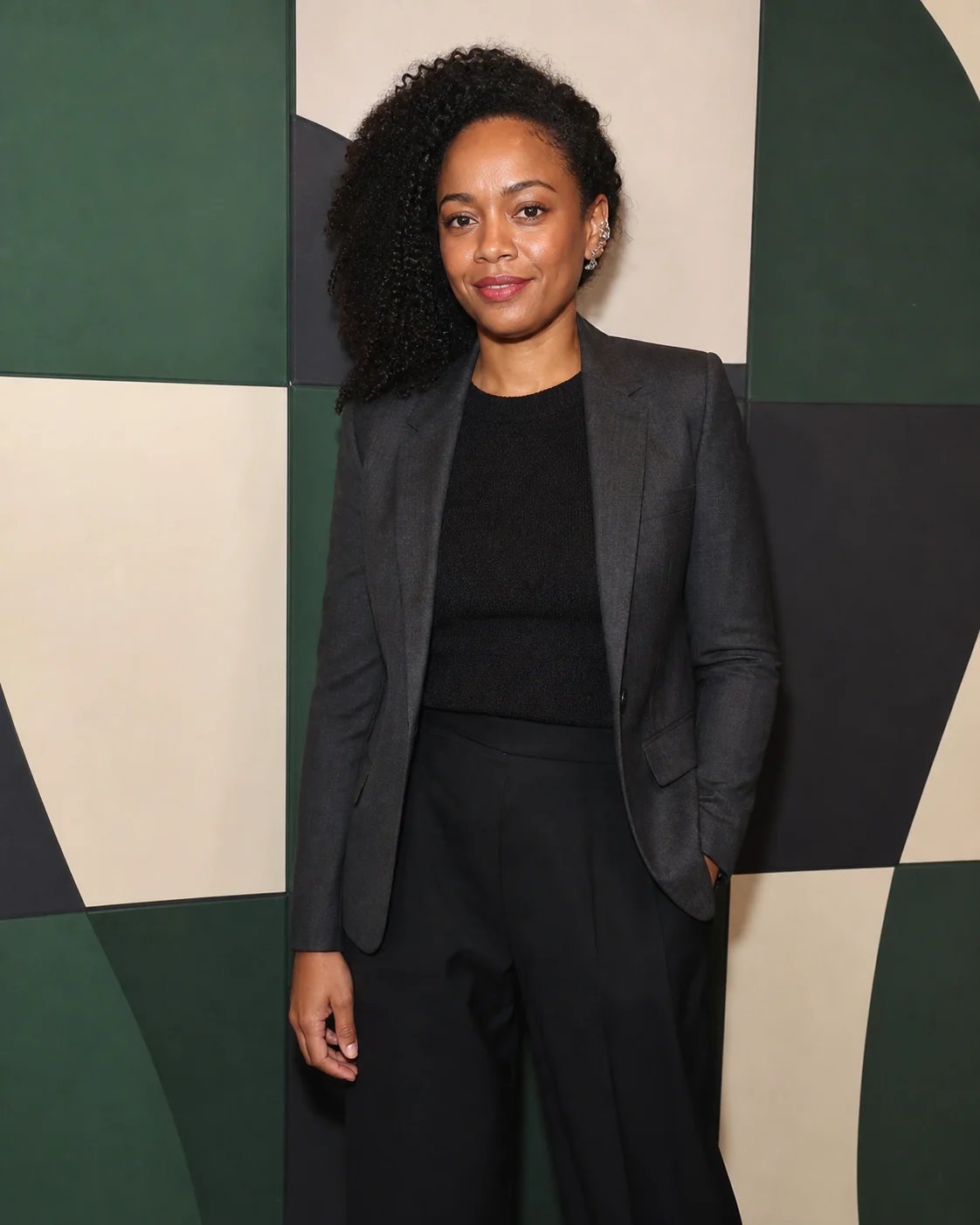 An attendee in charcoal tailoring photographed at a simple geometric festival photo wall