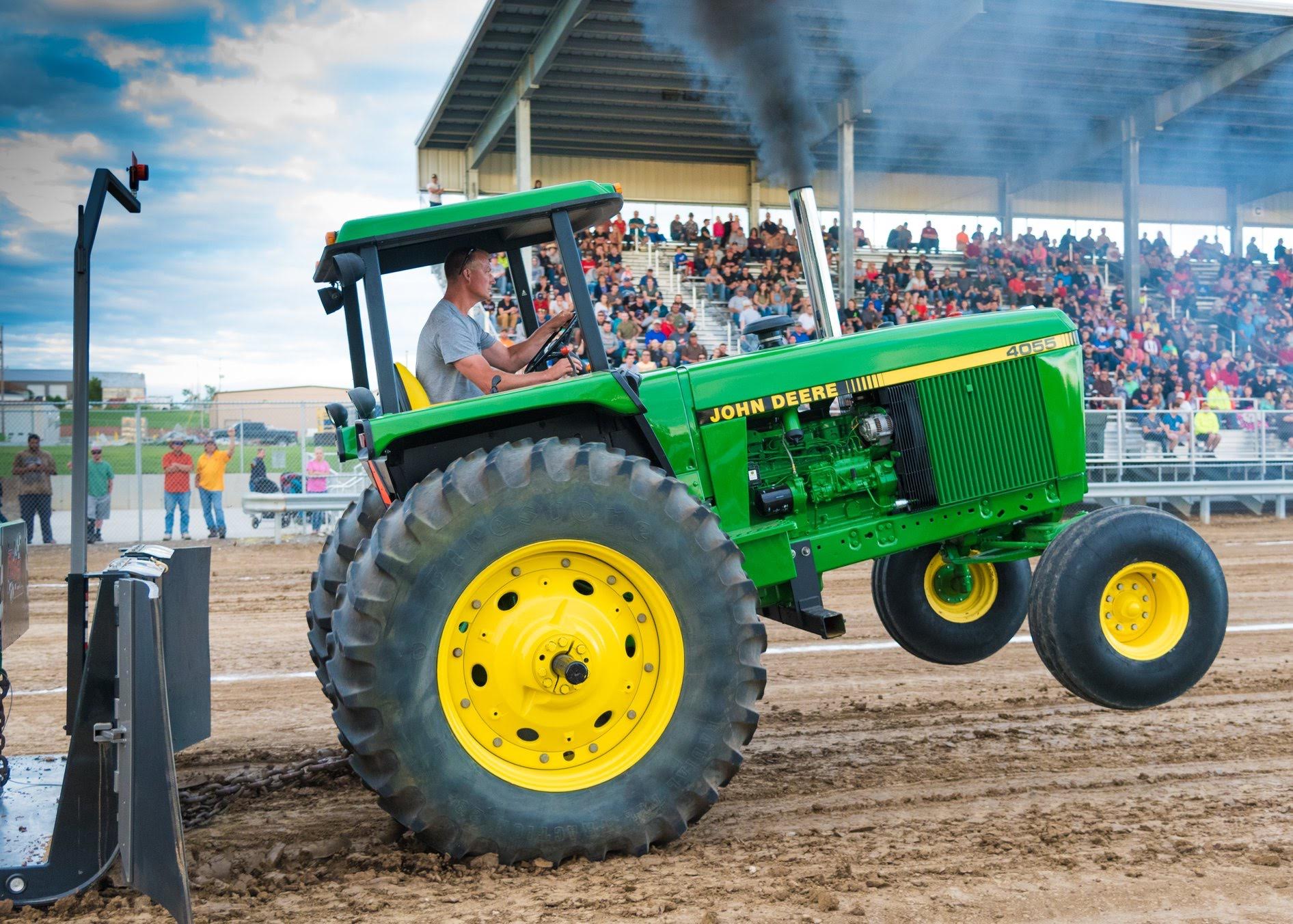 Man pulling a heavy trailer with his John Deere tractor at the Sarpy County Fair Tractor Pull. 