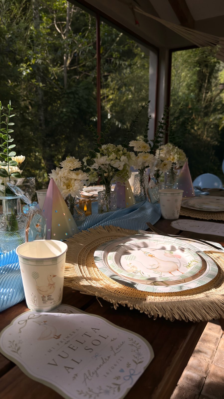 Mesa azul de primer cumpleaños con flores blancas, fibras naturales y letrero personalizado de ETERIA.
