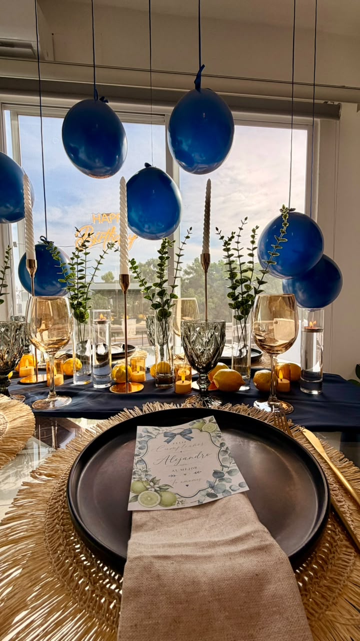 Lugar de mesa azul marino con limones, cristalería ámbar y velas blancas en celebración ETERIA.