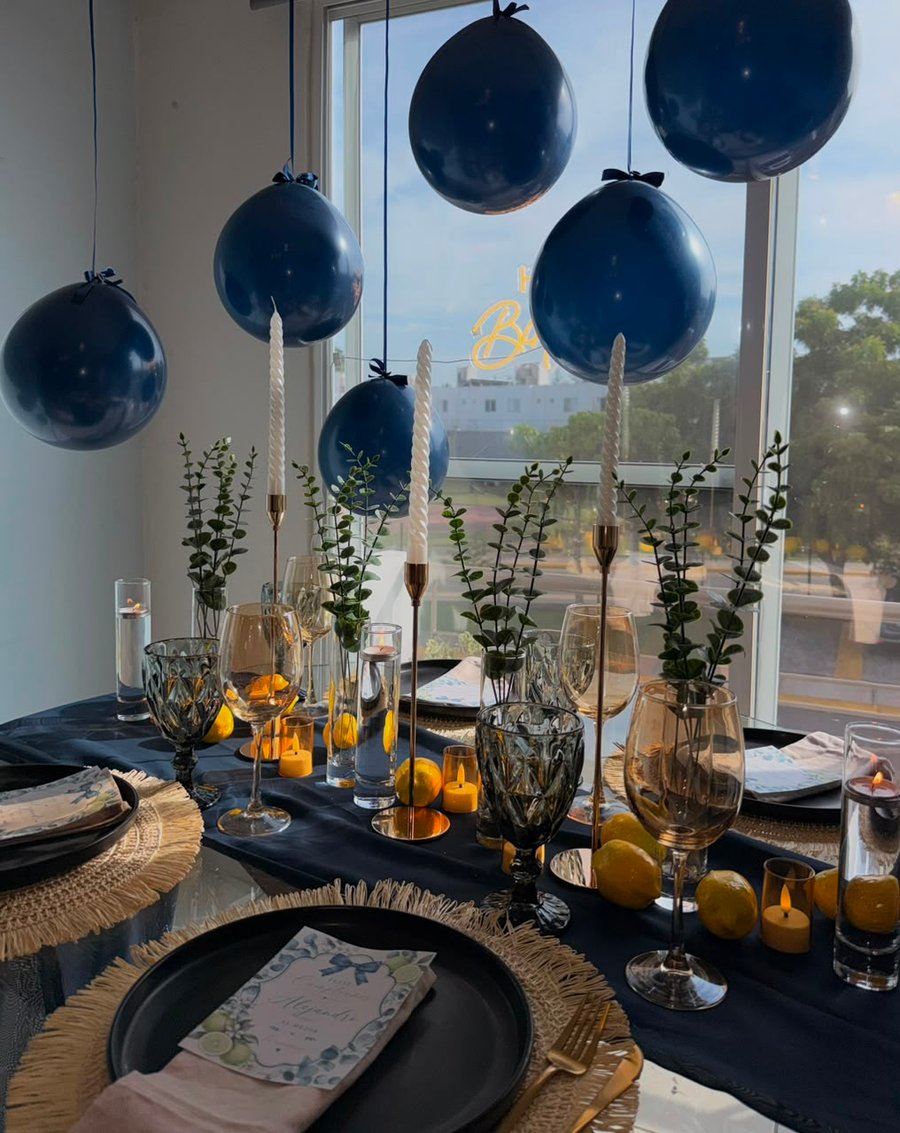 Ángulo de mesa azul marino con eucalipto, limones y cristalería ámbar de ETERIA.