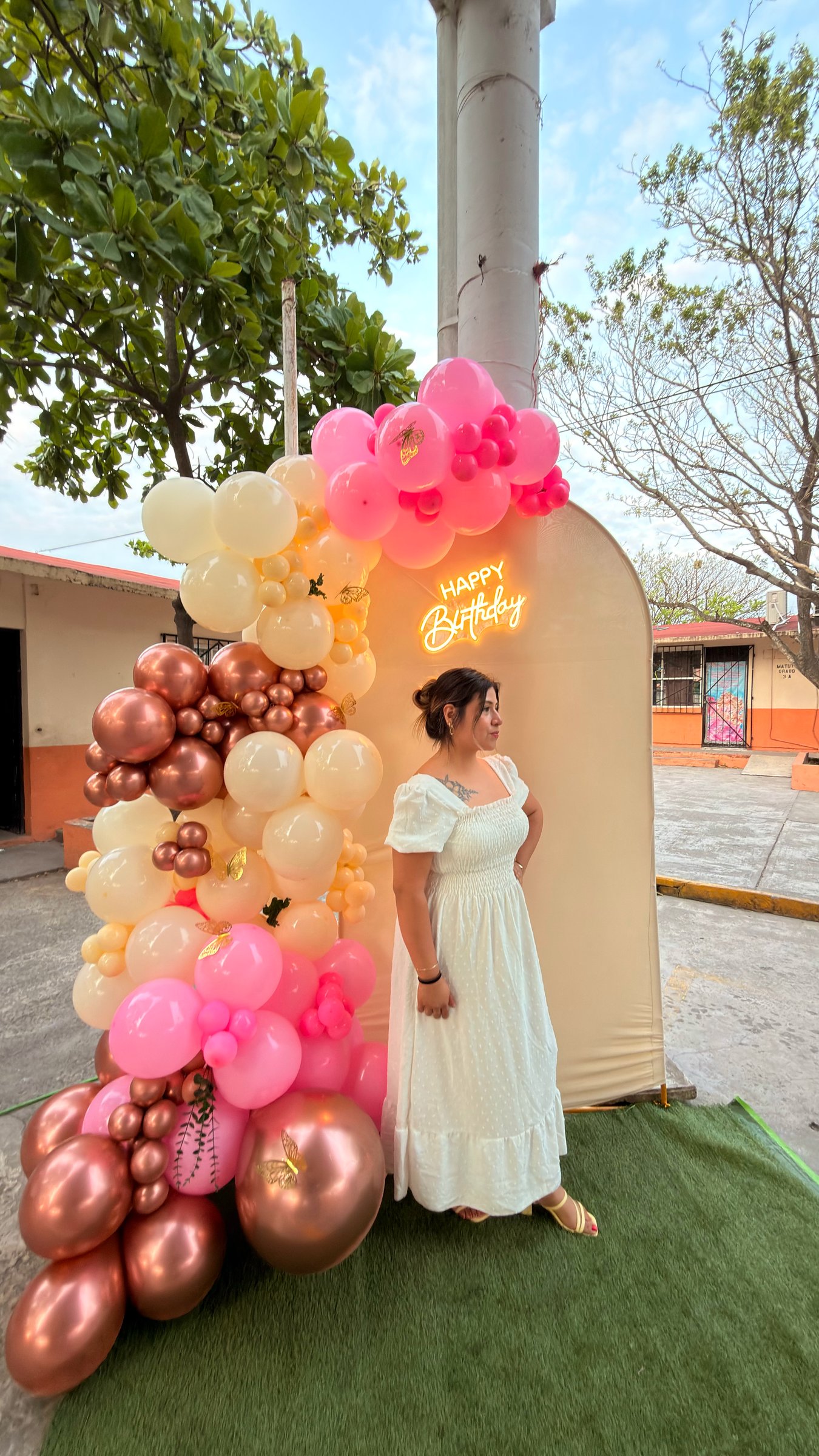 Invitada frente a un arco de globos rosa, marfil y cobre diseñado por ETERIA para un cumpleaños.