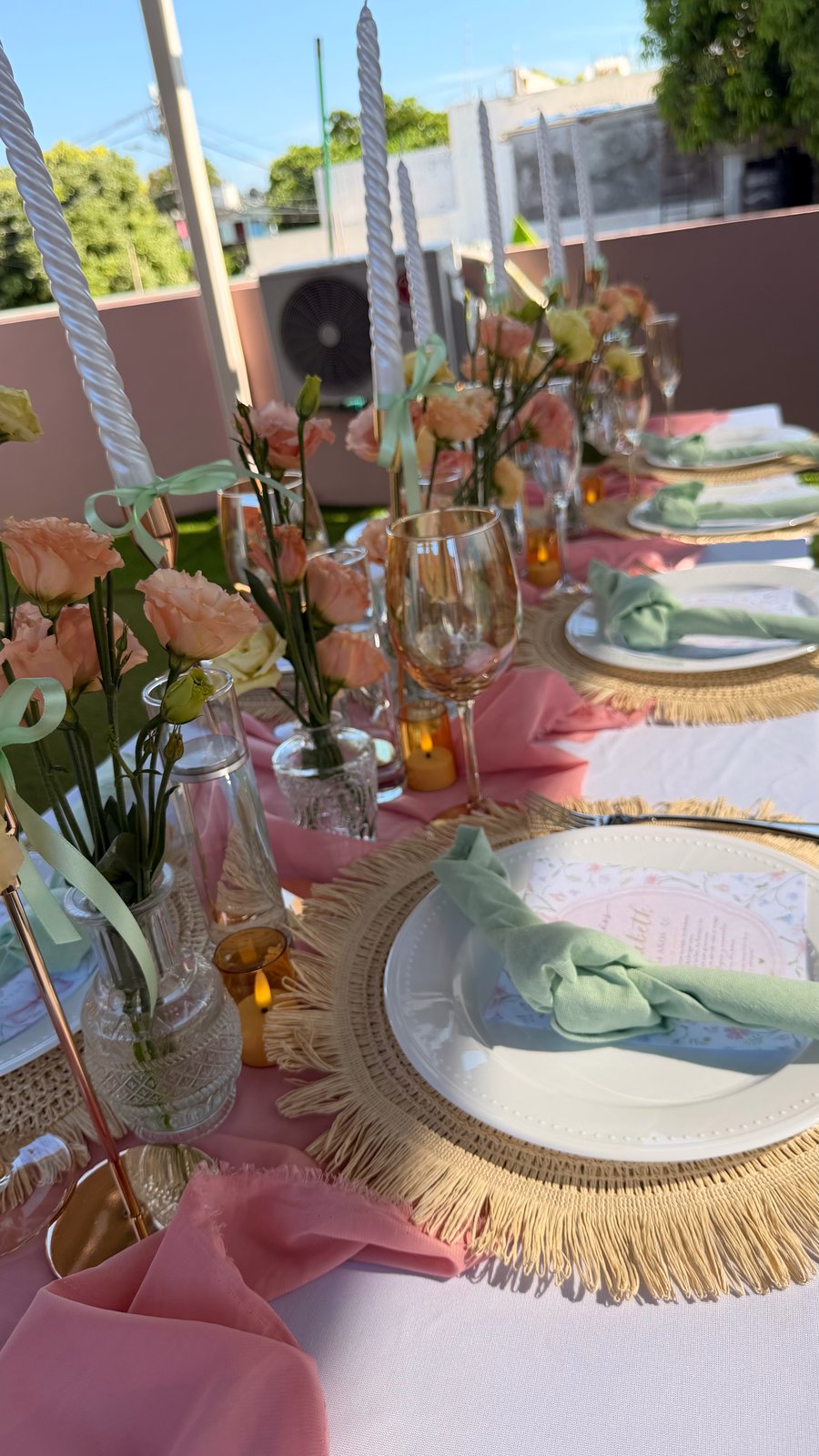 Vista longitudinal de mesa rosa con velas, flores y vajilla coordinada por ETERIA.