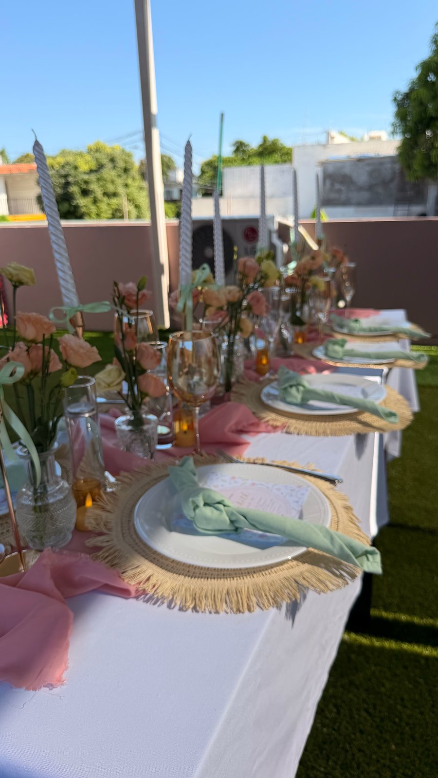 Mesa rosa de celebración con flores suaves, cristalería y velas altas en montaje ETERIA.