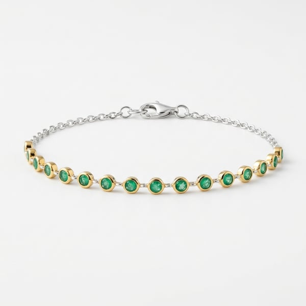 Jayda 925 sterling silver and gold accent bracelet with 18 small round emeralds on a white background.