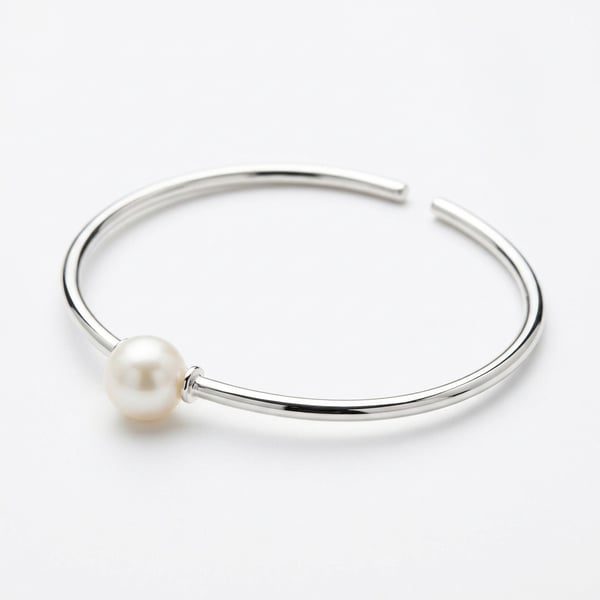 Studio shot of Raya 925 sterling silver open hoop bracelet featuring a single freshwater pearl.