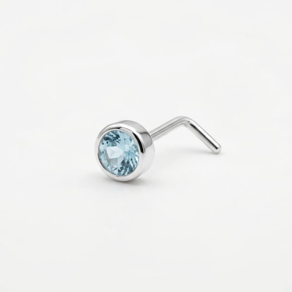 Studio shot of Kalilah sterling silver nose stud featuring a 3mm round aquamarine in an open bezel setting on a white background.