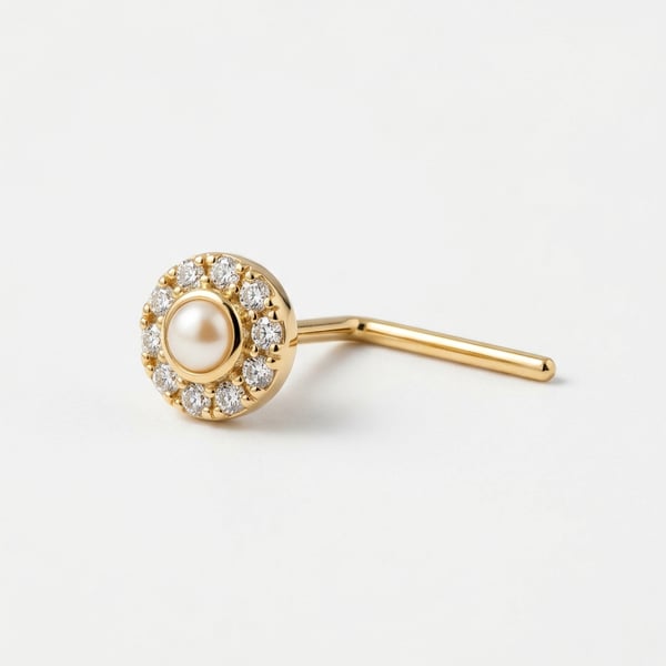 Studio macro photograph of an 18K gold L-shaped nose pin featuring a 2mm natural white pearl surrounded by a tiny halo of pav stones on a white background.
