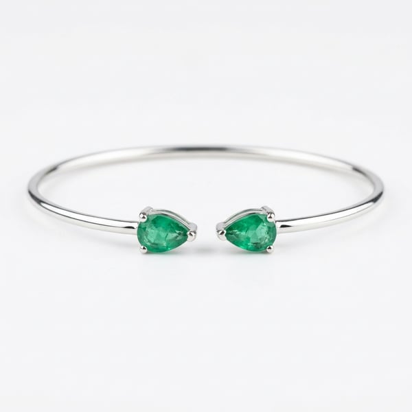 Sahirah open toi et moi sterling silver bracelet with two pear-cut natural emeralds on a white background